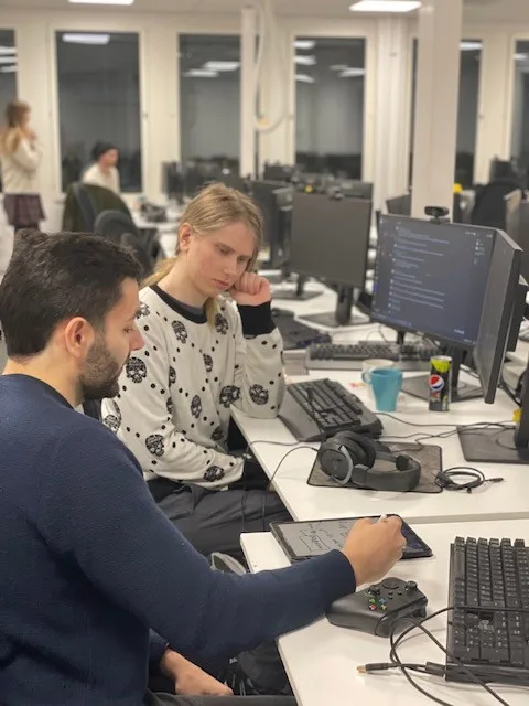 Two Futuregames students in classroom, working.
