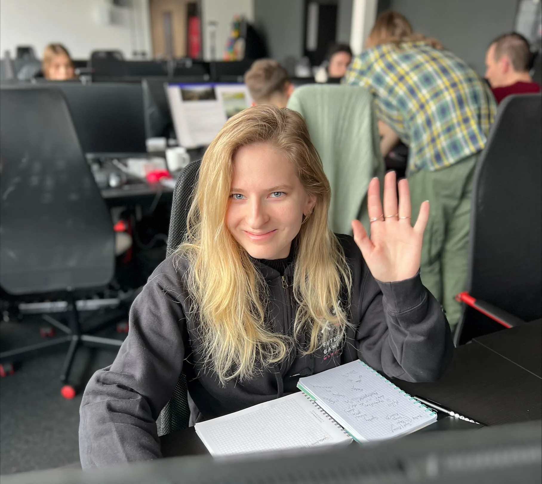 Futuregames Kamila Kuźmiuk in the classroom waving at the camera.