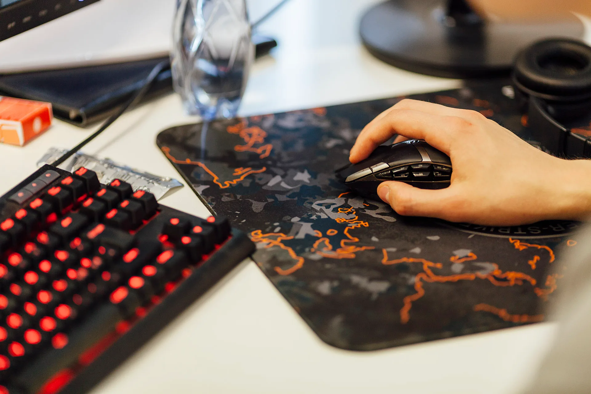 Hand on mouse by the computer setup.